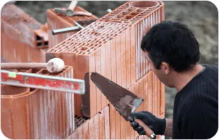 Murarz układający cegły.