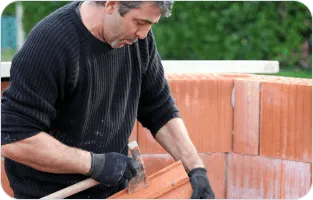 Murarz układający cegły.