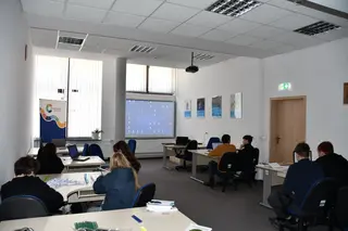 Powiększ obraz: Uczniowie biorący udział w prelekcji na sali szkoleniowej.