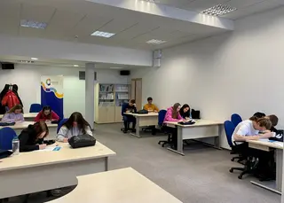 Powiększ obraz: Sala z biurkami, przy których siedzą uczniowie