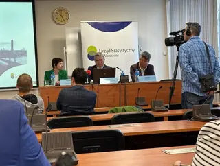 Powiększ obraz: Prowadzący konferencję siedzący przy stoliku